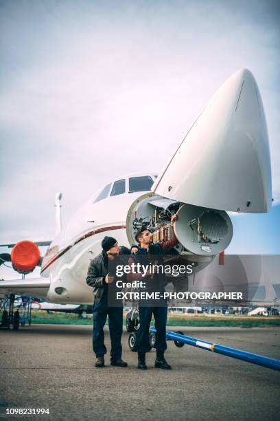 two aircraft engineers working on a sensor array under the nose cone of a private jet parked on an airport tarmac - aircraft maintenance stock pictures, royalty-free photos & images