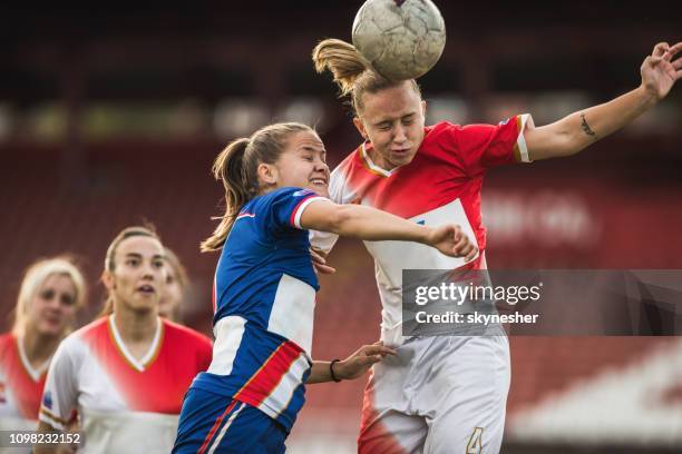 zwei weibliche fußball-rivalen ein match den ball unterwegs. - kopfball stock-fotos und bilder