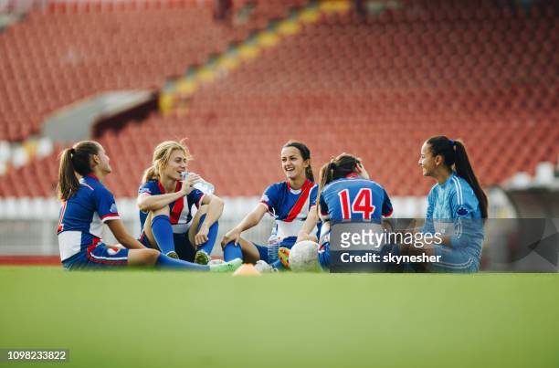 teenage soccer team relaxing on the grass and communicating. - groyne stock pictures, royalty-free photos & images