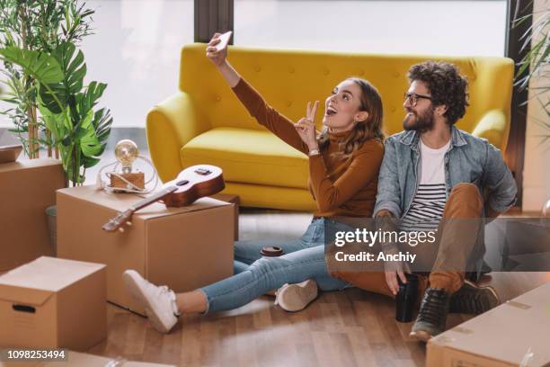 happy millennial couple taking selfie in new home - first apartment stock pictures, royalty-free photos & images