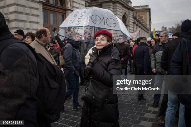 Woman stands under an umbrella with an anti-Orban slogan written on it during a demonstration against recent legislative measures introduced by...