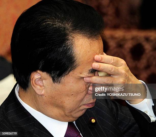 Japanese Prime Minister Naoto Kan covers his face with his hand during the Upper House's budget committee session at the National Diet in Tokyo on...