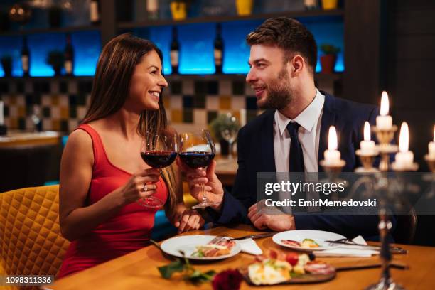 couple, appréciant le vin rouge le jour de la saint-valentin - diner amoureux photos et images de collection