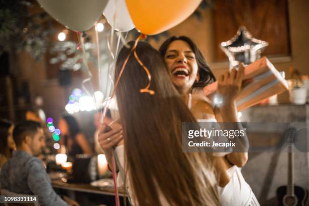 女性彼女のバースデー ディナー パーティーのゲストを歓迎し、贈り物を受け取る - gift ストックフォトと画像