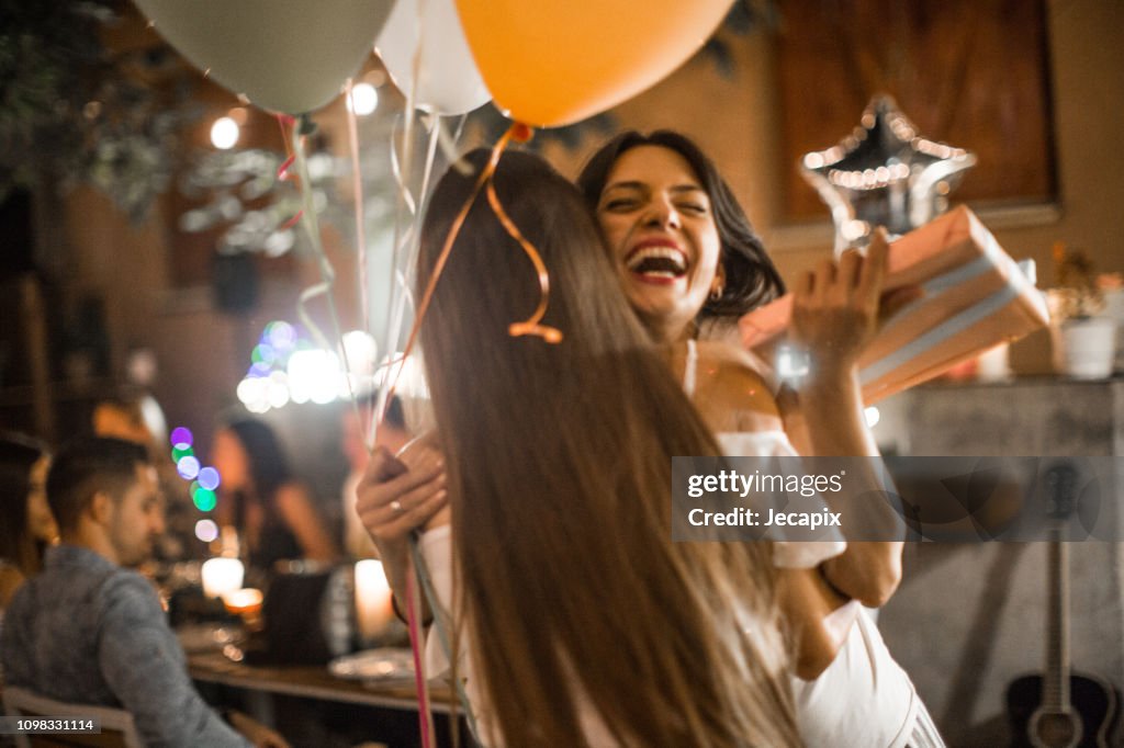 Vrouw gast te verwelkomen op haar verjaardagsfeestje voor diner en ontvangen van geschenken