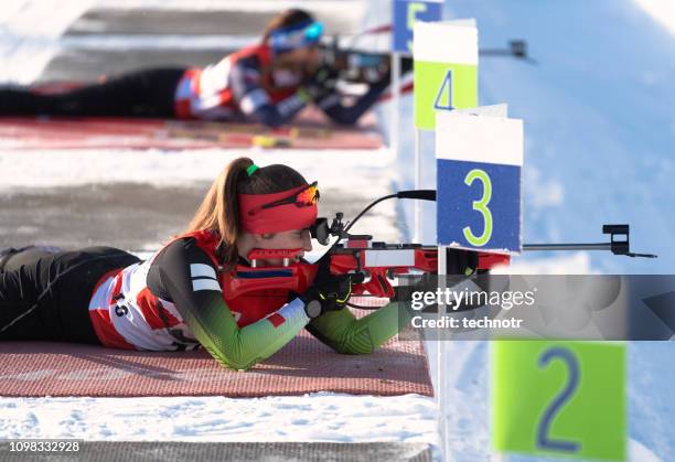 side view of two young female biathlon competitors practicing target shooting - biathlon ski stock pictures, royalty-free photos & images