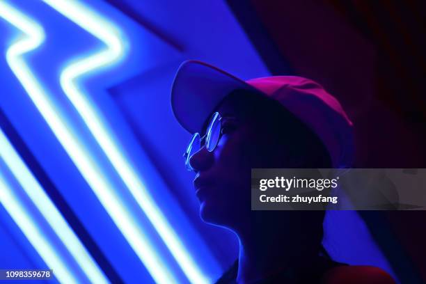 close-up portrait of young woman wearing sunglasses in darkroom - future party stock-fotos und bilder