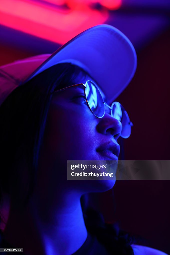 Close-Up Portrait Of Young Woman Wearing Sunglasses In Darkroom