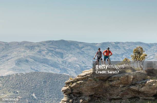 male mountainbikers posing on a cliff at andalucian sierra nevada, spain. - andalucian sierra nevada stock pictures, royalty-free photos & images