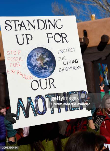 Participant in the 2019 Women's March holds a sign urging an end to fossil fuel extraction during a rally in Santa Fe, New Mexico.