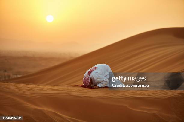 arab man praying on carpet in desert during sunset - prayer stock pictures, royalty-free photos & images