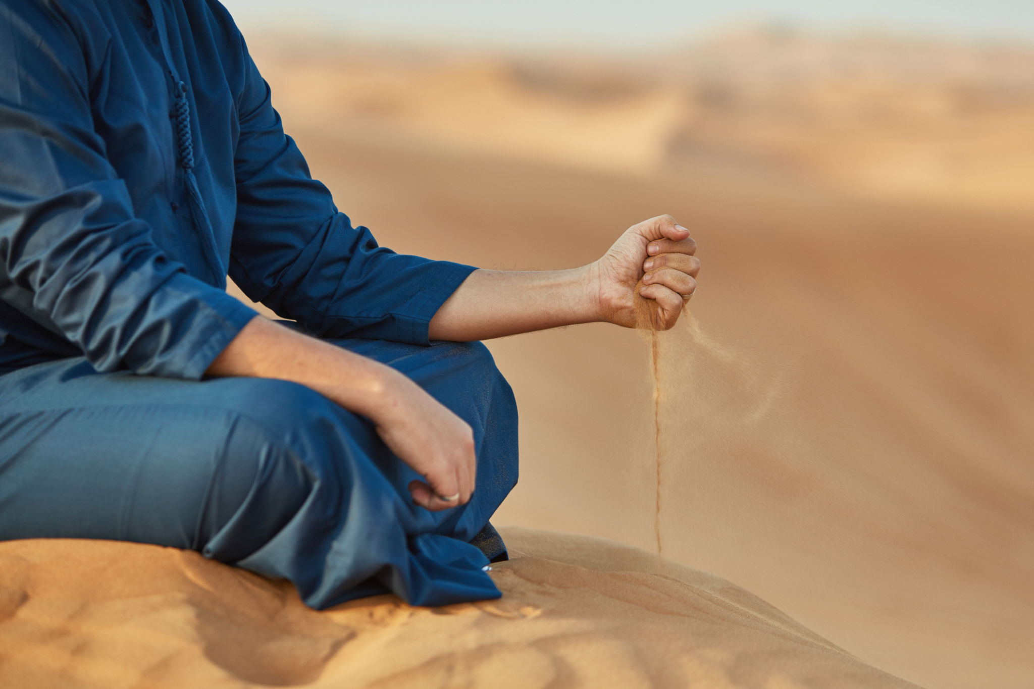 Low section of Arab man throwing sand in desert Low section of Arab man throwing sand in desert