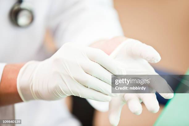doctor putting on examination gloves - surgical glove stock pictures, royalty-free photos & images