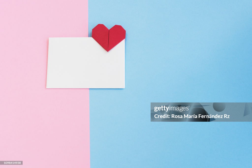 Valentine letter in open envelope with an origami  heart shape ready for love message on colored background. Copy space