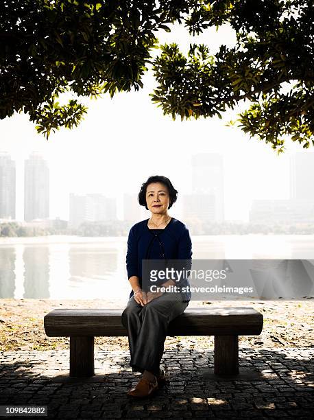senior woman sitting on a park bench - parkbänk bildbanksfoton och bilder
