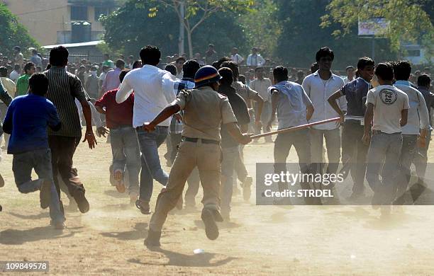 An Indian policeman runs towards a crowd with a lathi stick outside The Vidarbha Cricket Association Cricket Stadium in Nagpur on March 8 as...