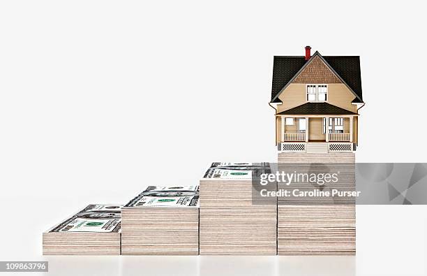 four stacks of money with a house on the highest - house on white backgroud imagens e fotografias de stock