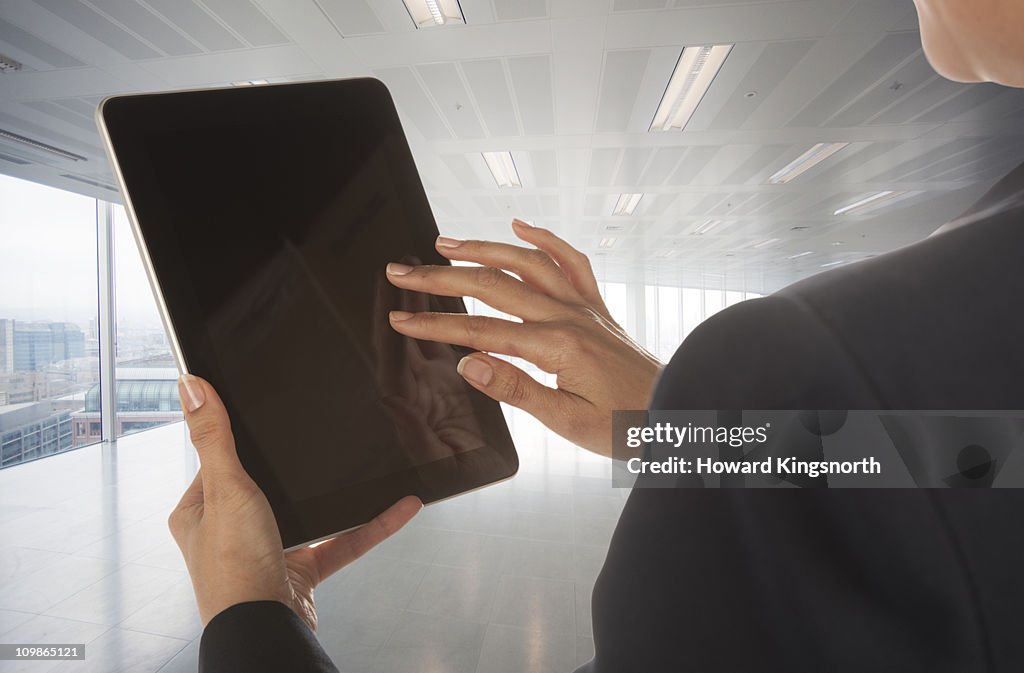 Female operating digital tablet tablet in empty office