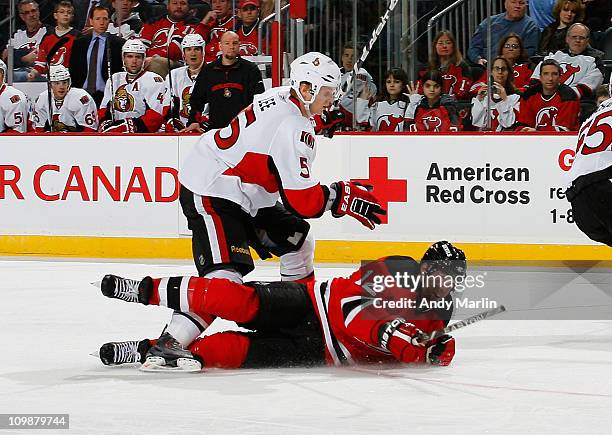 Brian Lee of the Ottawa Senators knocks Brian Rolston of the New Jersey Devils to the ice during the game at the Prudential Center on March 8, 2011...