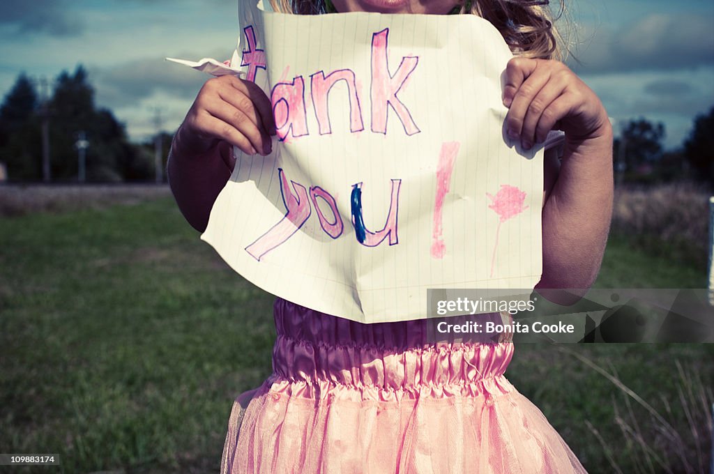 Girl in fairy dress holding 'thank you' sign