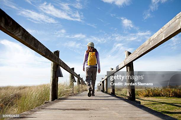 female walking along boardwalk. - cannon beach foto e immagini stock