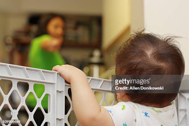 baby boy sees mom in the kitchen - baby gate stock pictures, royalty-free photos & images
