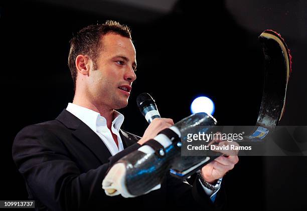 Palaympics Champion Oscar Pistorius holds one of his running legs as he gives a speech during the Global Sports Forum day 1 on March 10, 2011 in...