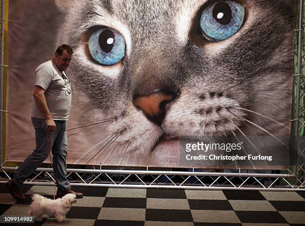 Man walks his dog past an advertisement for cat food on the first day of the annual Crufts dog show for the Gun Dogs section at the National...