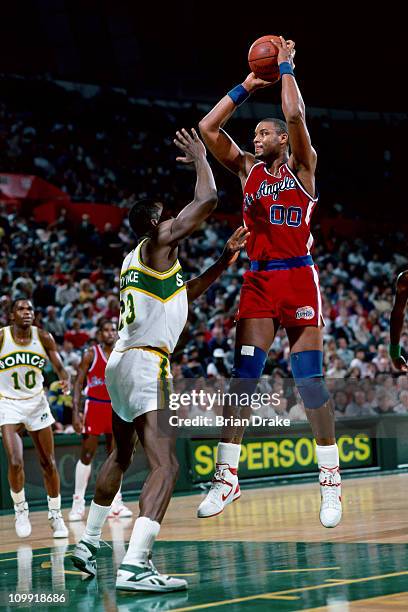 Benoit Benjamin of the Los Angeles Clippers shoots against Olden Polynice of the Seattle Supersonics circa 1990 at the Seattle Coliseum in Seattle,...