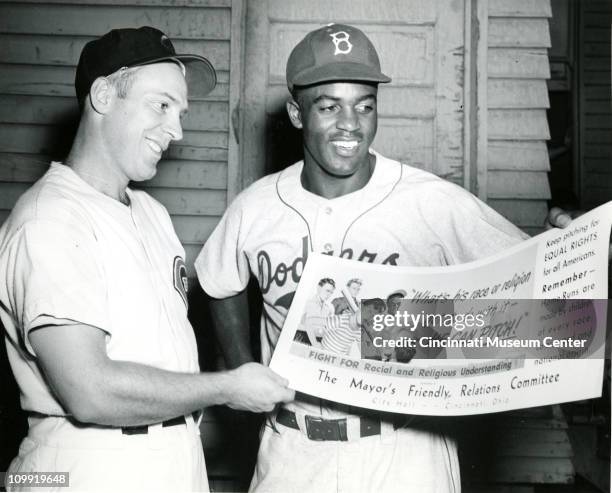 American baseball players Danny Litwhiler of the Cincinnati Reds and Jackie Robinson of the Brooklyn Dodgers pose together as they smile and hold a...