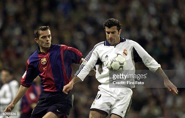 Lusi Figo of Real Madrid holds off Philip Cocu of Barcelona during the Real Madrid v FC Barcelona La Liga match played at the Santiago Bernabeau,...