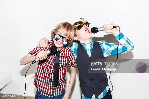 two boys singing into microphones - boy singing stock-fotos und bilder