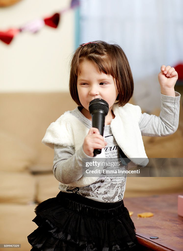 Toddler, singing, arm raised, fist, looking away