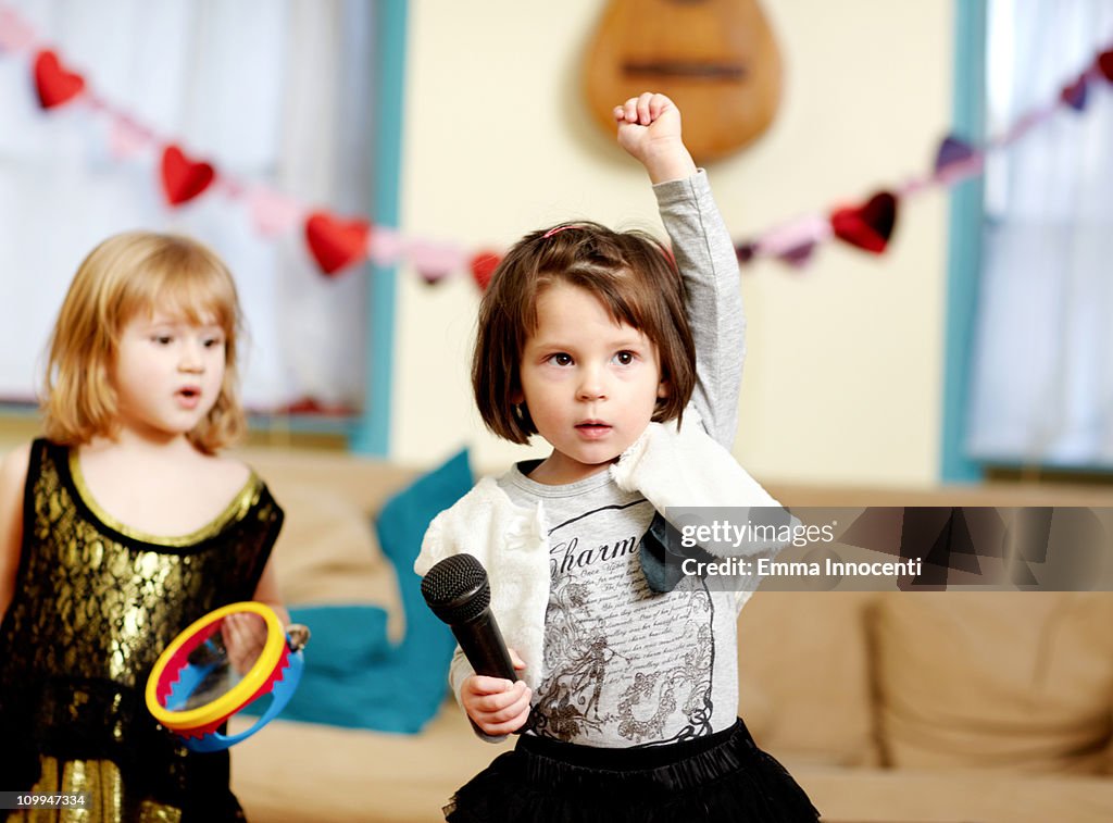 Toddler, one arm raised, microphone, serious