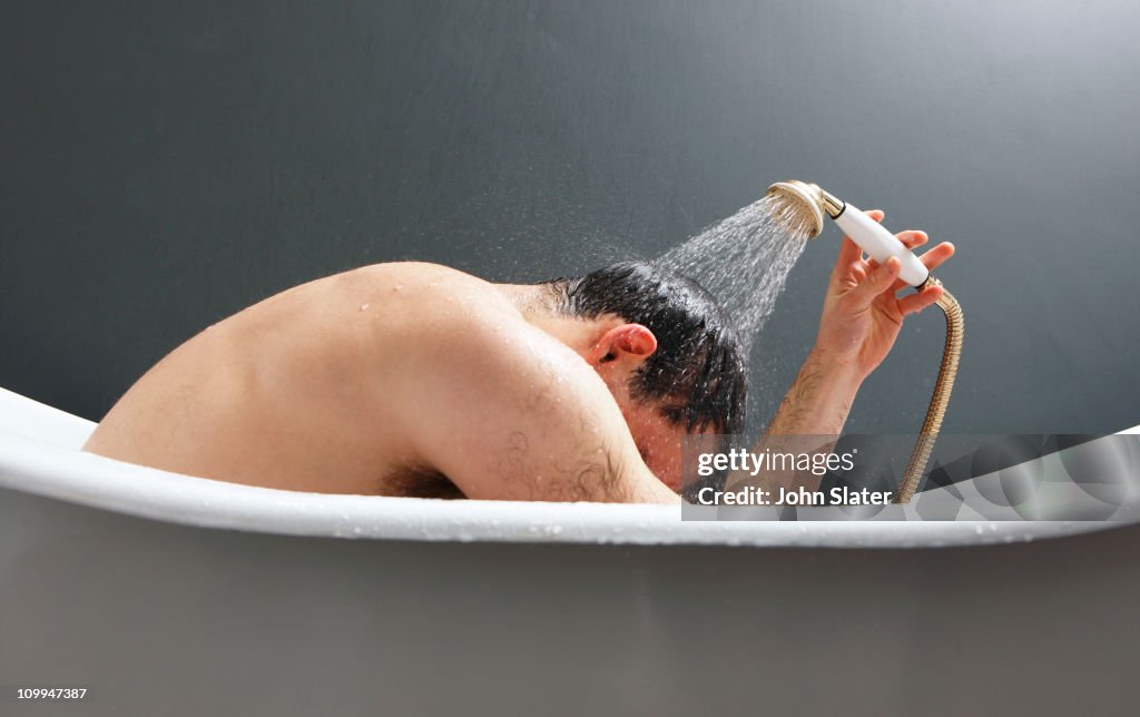 Man using shower in bath tub