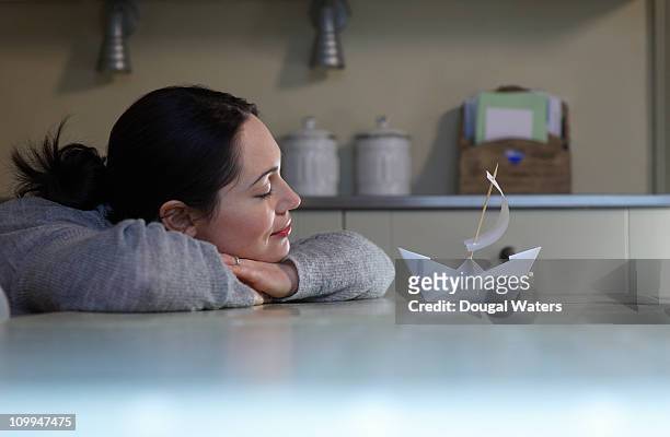 woman daydreaming in kitchen - paper boat stock-fotos und bilder