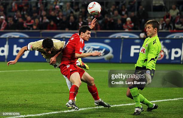 Karim Haggui of Hannover goes up for a header with Mato Jajalo and goalkeeper Michael Rensing of Koeln during the Bundesliga match between 1. FC...