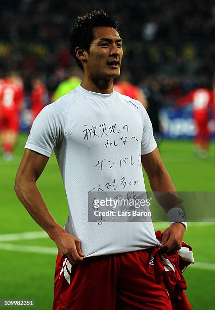 Tomoaki Makino of Koeln shows a shirt for the victims of the earthquake in his home country Japan after winning the Bundesliga match between 1. FC...