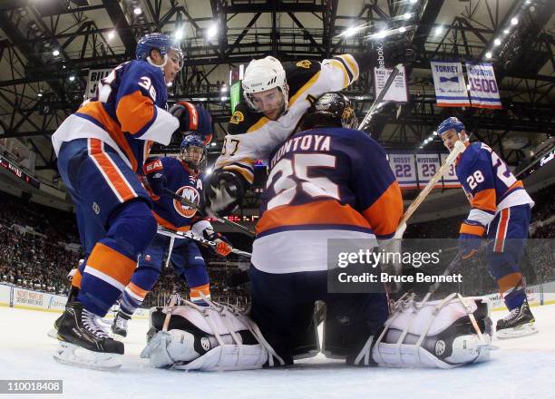 Travis Hamonic and Al Montoya of the New York Islanders defend the net against Patrice Bergeron of the Boston Bruins at the Nassau Coliseum on March...