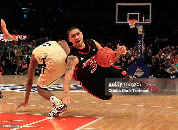 Peyton Siva of the Louisville Cardinals falls while trying to dribble around Eric Atkins of the Notre Dame Fighting Irish during the semifinals of...