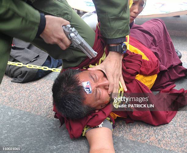 Supporter of Tibetan spiritual leader Dalai Lama dressed up as a Chinese soldier points a "gun" at a Tibetan monk during a rally in Taipei on March...