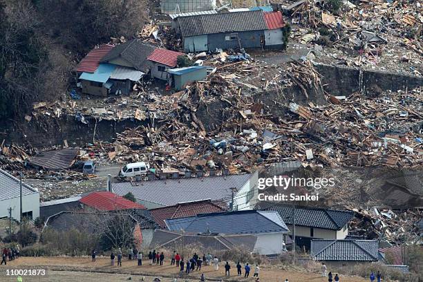 In this aerial image, people look at destroyed houses on March 12, 2011 in Minamisanriku, Miyagi, Japan. An earthquake measuring 8.9 on the Richter...