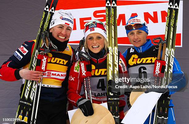 Justyna Kowalczyk of Poland, Therese Johaug of Norway and Arianna Follis of Italy pose on the podium after the women's 5km pursuit of the FIS World...