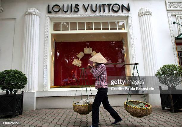 A Vietnamese woman walks by the Louis Vuitton shop in the French