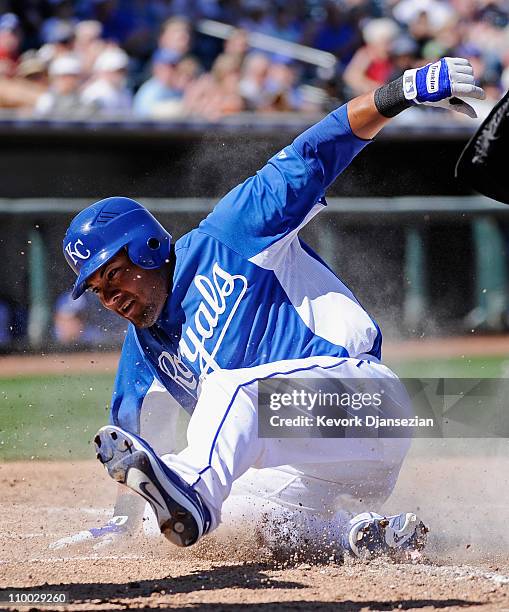 Melky Cabrera of the Kansas City Royals slides at home plate to score a run during the fourth inning of the spring training baseball game against the...