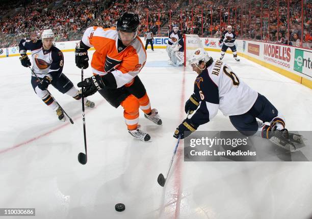 Ville Leino of the Philadelphia Flyers battles in the corner for the loose puck with Alexander Burmistrov and Ron Hainsey of the Atlanta Thrashers on...