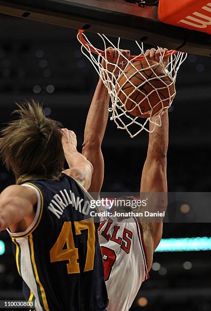 Joakim Noah of the Chicago Bulls dunks the ball against Andrei Kirilenko of the Utah Jazz at the United Center on March 12, 2011 in Chicago,...