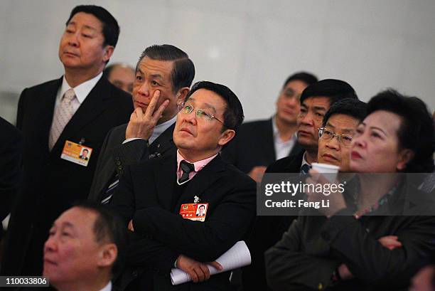 The delegates watch TV and pay close attention to the news of Japan's earthquake before the closing session of the Chinese People's Political...