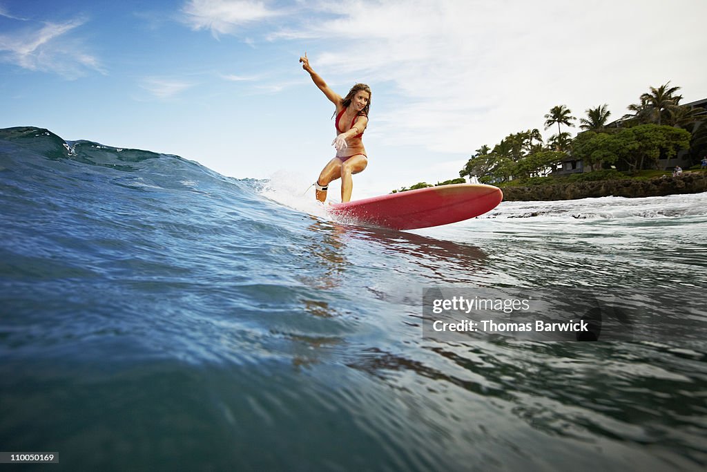 Female surfer riding wave view from water