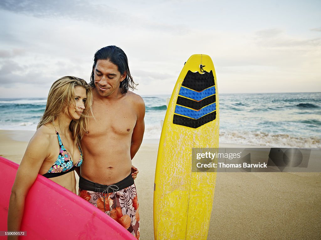 Husband and wife on beach with surfboards